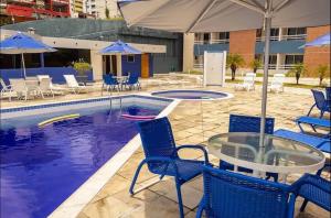 a pool with chairs and a glass table and umbrellas at MoviHosts Terrazzo in Natal