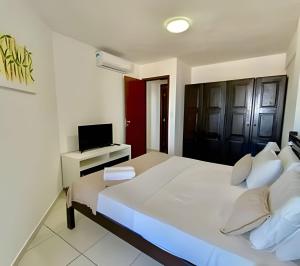 a bedroom with a large white bed and a television at MoviHosts Terrazzo in Natal +34 photos