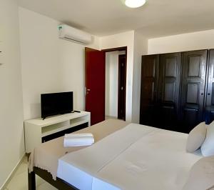 a white bedroom with a bed and a television at MoviHosts Terrazzo in Natal