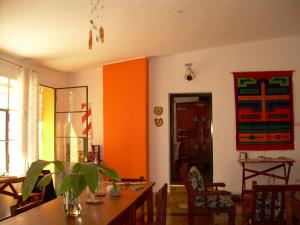 a dining room with a table and an orange wall at Hostería Villa Luz Habitación 1 in San Marcos Sierras +5 photos