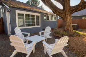 four white chairs and a table in front of a house at Charming Cozy Cottage with Hot Tub in Coeur d'Alene