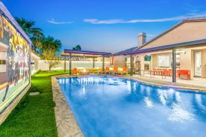 a swimming pool in front of a house at Hollywood Hideaway with 158" Poolside TV and 2 Arcades in Indio