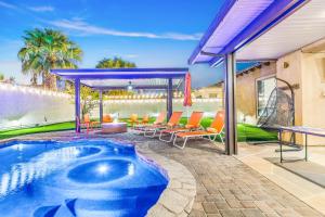 a swimming pool on a patio with orange chairs at Hollywood Hideaway with 158" Poolside TV and 2 Arcades in Indio +156 photos