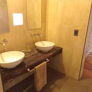 ein Badezimmer mit zwei Waschbecken auf einer Holzplatte in der Unterkunft Casa Müller Mendoza in Ciudad Lujan de Cuyo