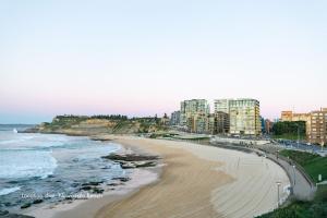 a view of a beach with buildings and the ocean at The Wave in Newcastle