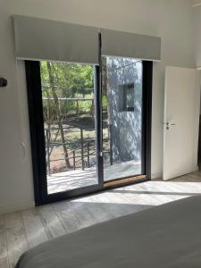 a bedroom with a large window with a view of a yard at Cabaña Panpachay Villa Giardino in Villa Giardino +9 photos