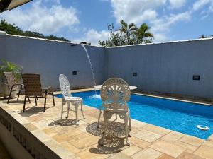 a patio with chairs and a swimming pool at Casa com Piscina na Enseada in Guarujá