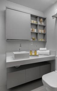 un bagno bianco con lavandino e specchio di Praia de Cabo Branco - Espaço Privativo - Conforto - Lazer - Luxo a João Pessoa