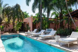 a swimming pool with chaise lounges and chairs next to a house at Casa Bella Cruz in Cruz de Huanacaxtle