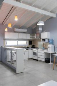 eine große Küche mit weißen Schränken und einem Tisch in der Unterkunft La Casona Apart & Suites in Ezeiza