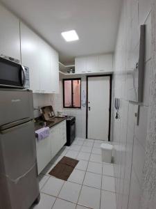 a kitchen with white cabinets and a white tile floor at Casa aconchegante perto da praia in Salvador +4 photos