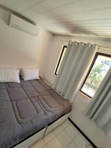 a small bedroom with a bed and a window at Casa aconchegante perto da praia in Salvador