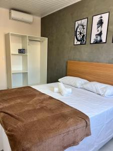 a bedroom with a large bed with a clock on the wall at LOFT PAJUMAR 1 ANDAR 300mt PRAIA PAJUCARA in Maceió