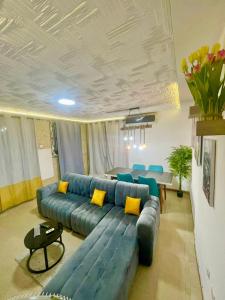 sala de estar con sofá azul y almohadas amarillas en Appartement Grace, en Abiyán