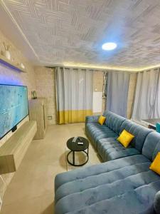 Una sala de estar con un sofá azul y un televisor de pantalla plana. en Appartement Grace, en Abiyán