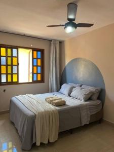 - une chambre avec un lit, un ventilateur de plafond et une fenêtre dans l'établissement Casa encantadora com vista para o lago, à Cabo Frio