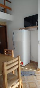 a kitchen with a refrigerator and a table and a television at El nuevo amanecer mar de ajó in Mar de Ajó +3 photos