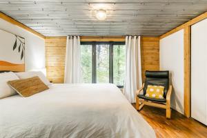a bedroom with a large bed and a chair at Le 14 Chalets Howard - Spa-Shower-Hammock-Bromont in Bromont