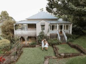 Una mujer y una niña paradas frente a una casa en The Little Queenslander - Maleny Circa 1888, en Balmoral Ridge