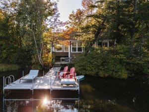 a dock with chairs and a house on the water at The Owl's Nest - Lakeside peacefulness ski & hiking in Austin