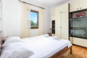 a bedroom with a large white bed and a window at Apartments by the sea Postira, Brac - 739 in Postira