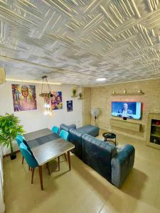 Una sala de estar con un sofá, una mesa y un televisor. en Appartement Grace, en Abiyán