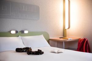 a bedroom with a bed with a book and a table at ibis budget Pontault Combault RN4 Marne La Vallée in Pontault-Combault +35 photos