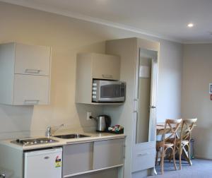 a kitchen with a sink and a microwave at Albert Court Motor Lodge in Hamilton +33 photos