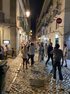 a group of people walking down a street at night at historic hearth of Bairro Alto in Lisbon
