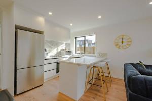 a white kitchen with a refrigerator and a counter at City Centre Elegance Apt 3 in Hamilton