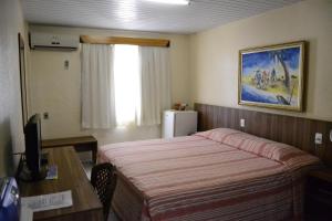 a hotel room with a bed and a desk and a television at Hotel Casa De Praia in Fortaleza