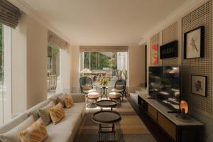a living room with a couch and a flat screen tv at Capella Singapore in Singapore