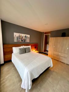 1 dormitorio con cama blanca y pared gris en Aparta-Suite en Garagoa ubicación central., en Garagoa