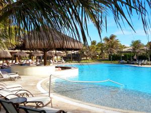 a swimming pool with chairs and umbrellas at a resort at Dom Pedro Laguna Beach Resort & Golf in Aquiraz