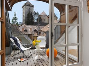 een open deur naar een balkon met stoelen en een sinaasappel bij Le Loft d'Annecy - Vision Luxe in Annecy