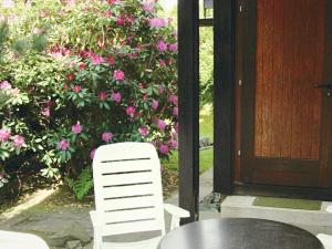 a table and a white chair in front of a bush of flowers at Furnished Bungalow With Peaceful Neighbourhood in Meschede