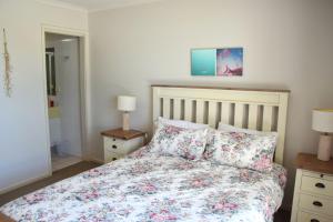 een slaapkamer met een bed met een bloemenbed en 2 lampen bij Jubilee Apartment 04 - Bring your own linen in South West Rocks +8 foto's
