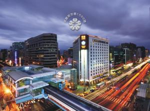 a city at night with a clock on top of a building at Brother Hotel in Taipei