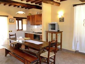 a kitchen with a wooden table and a tv at Belvilla by OYO Villa Roseto in Poggioni