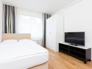 a bedroom with a bed and a flat screen tv at Swiss Star Longstreet - Self Check-In in Zurich