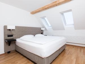 a bedroom with a large white bed and windows at Swiss Star Longstreet - Self Check-In in Zurich