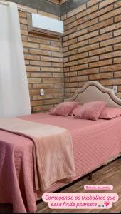 una camera con letto rosa e muro di mattoni di Chalé de Pedra a Praia Grande