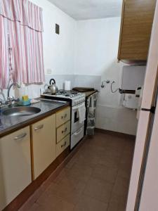 Una pequeña cocina con estufa y fregadero. en Lo de Juan, en Villa General Belgrano