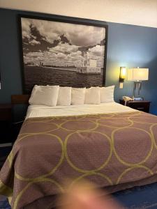 Valued Stay Prairie Du Chien في برايري دو شين: سرير في غرفة الفندق مع لوحة على الحائط