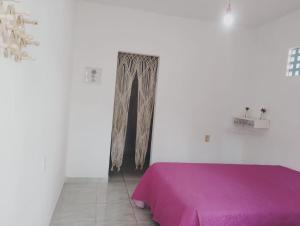 a white room with a purple bed and a doorway at Suíte Vila das Àguas - 150m da praia in Alter do Chao