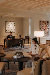 a woman sitting on a couch in a living room with a piano at Capella Singapore in Singapore +37 photos