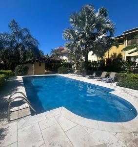 a large blue swimming pool with chairs and a palm tree at La Casita de Naomi in Tamarindo