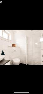 a white bathroom with a toilet and a sink at Øyperlen in Hernar