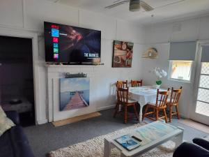 a living room with a table and a television above a fireplace at The Boathouse a 3 Bedroom Holiday Home in Narooma