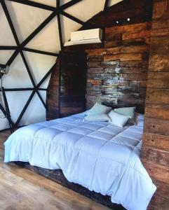 a large bed in a room with a wooden wall at Domos munaQ in San Javier